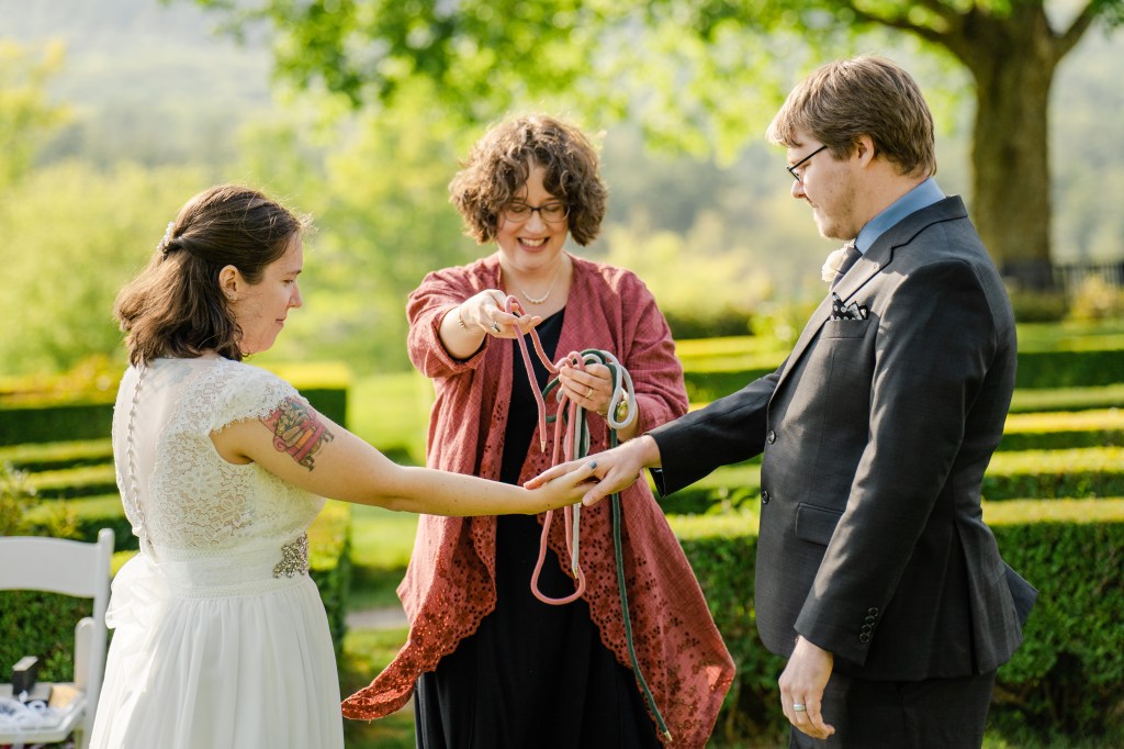 Kristabeth placing handfasting chords over the hands of the wedding couple. 